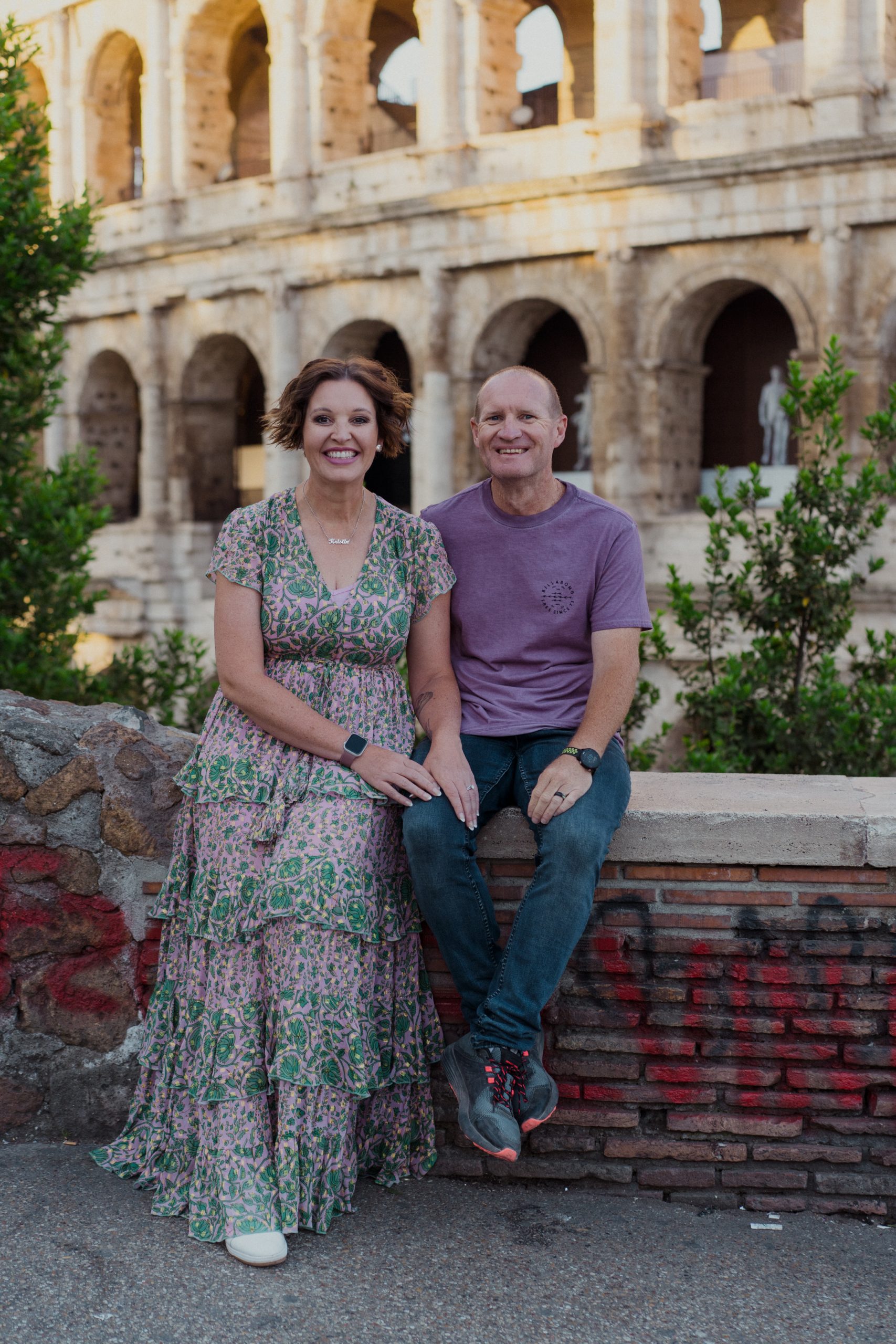 Portrait of Krissi and Peter seated in front of the Colosseum in Rome, Italy